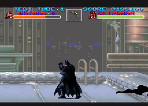 Batman stands alone on a snow-dusted rooftop in front of a tall industrial wall, with the Bat-signal projected onto the wall as a pixel-dot matrix, Catwoman's silhouette lying defeated to the right edge of frame.