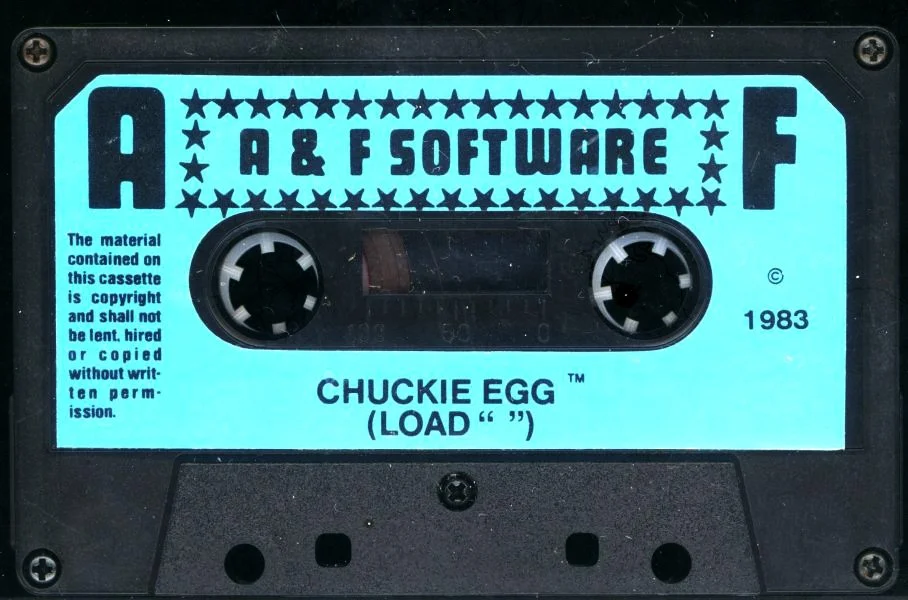 Black-and-cyan A&F Software cassette label for Chuckie Egg, copyright 1983, with the loading instruction LOAD double-quote double-quote printed beneath the title.