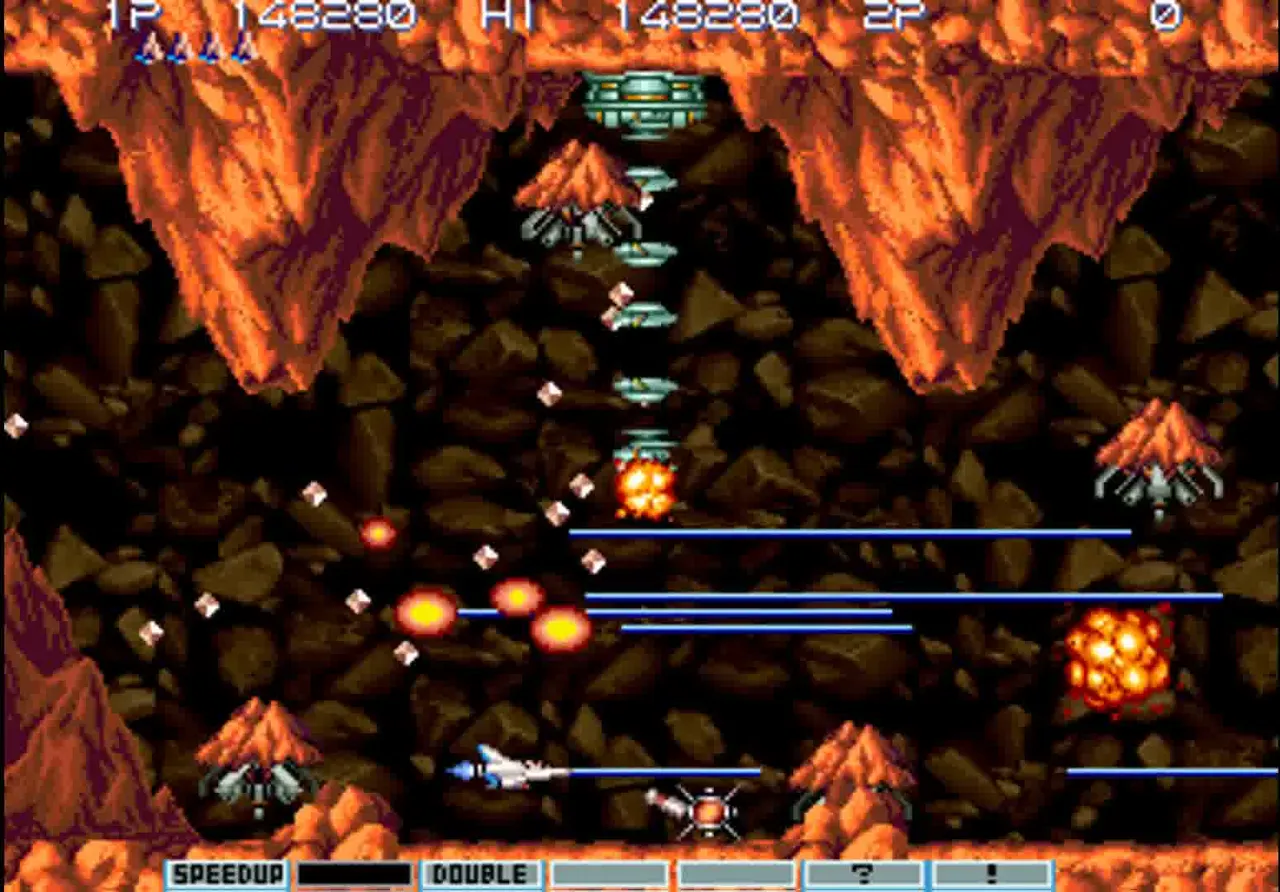 The arcade Volcanic Planet stage — Vic Viper firing parallel blue lasers through a vertical canyon of orange volcanic rock, multiple turret enemies arranged across the screen, twin missile racks tracking the ship.