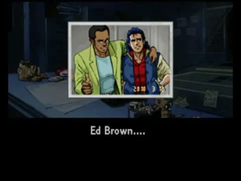A photograph held up on a desk: Ed Brown in a yellow jacket and Jonathan Ingram in a red bandana, dialogue box reading 'Ed Brown....'
